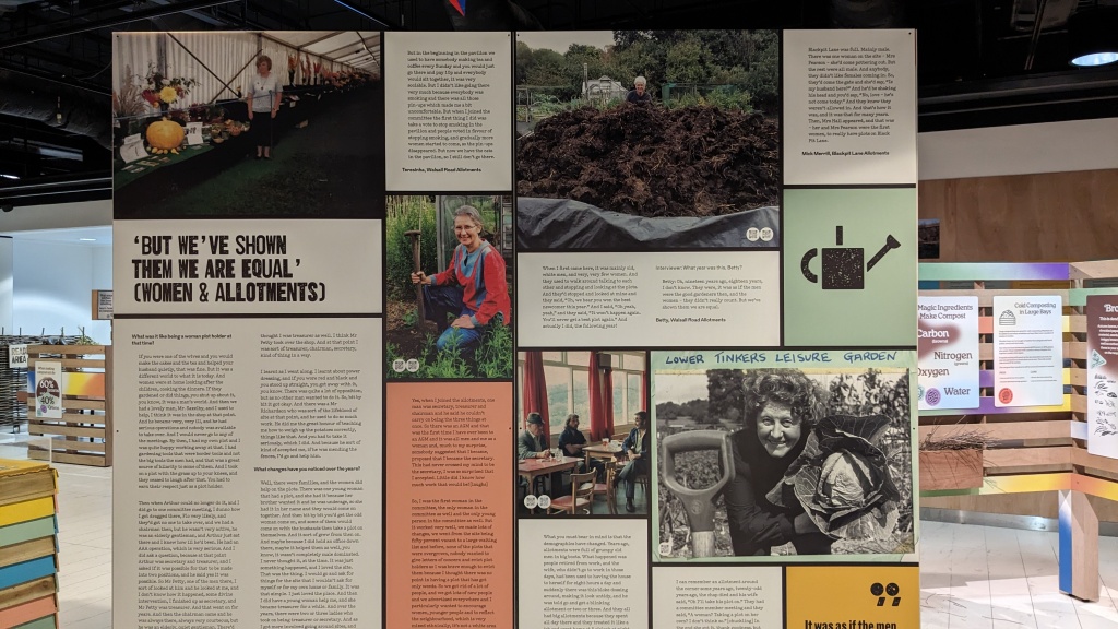 One of the board in the exhibtion. The design shows the title "But We've shown then we are equal" (Women & Allotments) along side the text of interviews (illegible) and 5 photographs of different women smiling and standing in thier allotment spaces